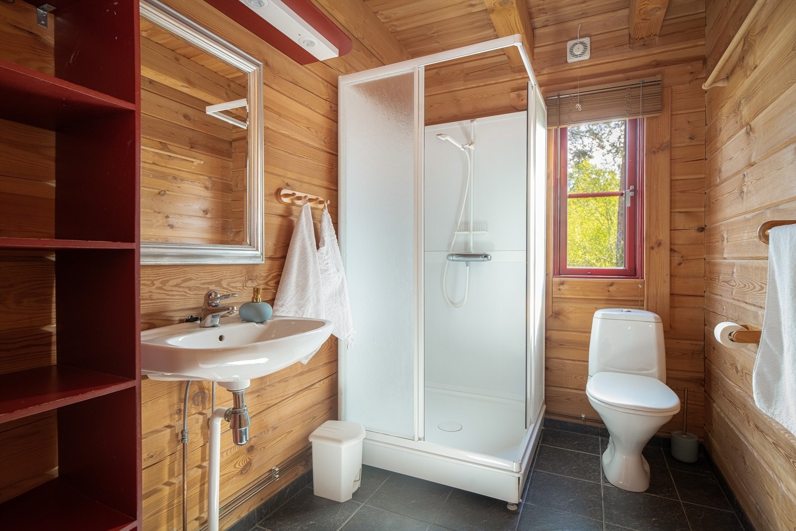 Badet i 1. etasje har adkomst fra stua, med flislagt gulv og tømmervegger som i hytta for øvrig. Galleribilde