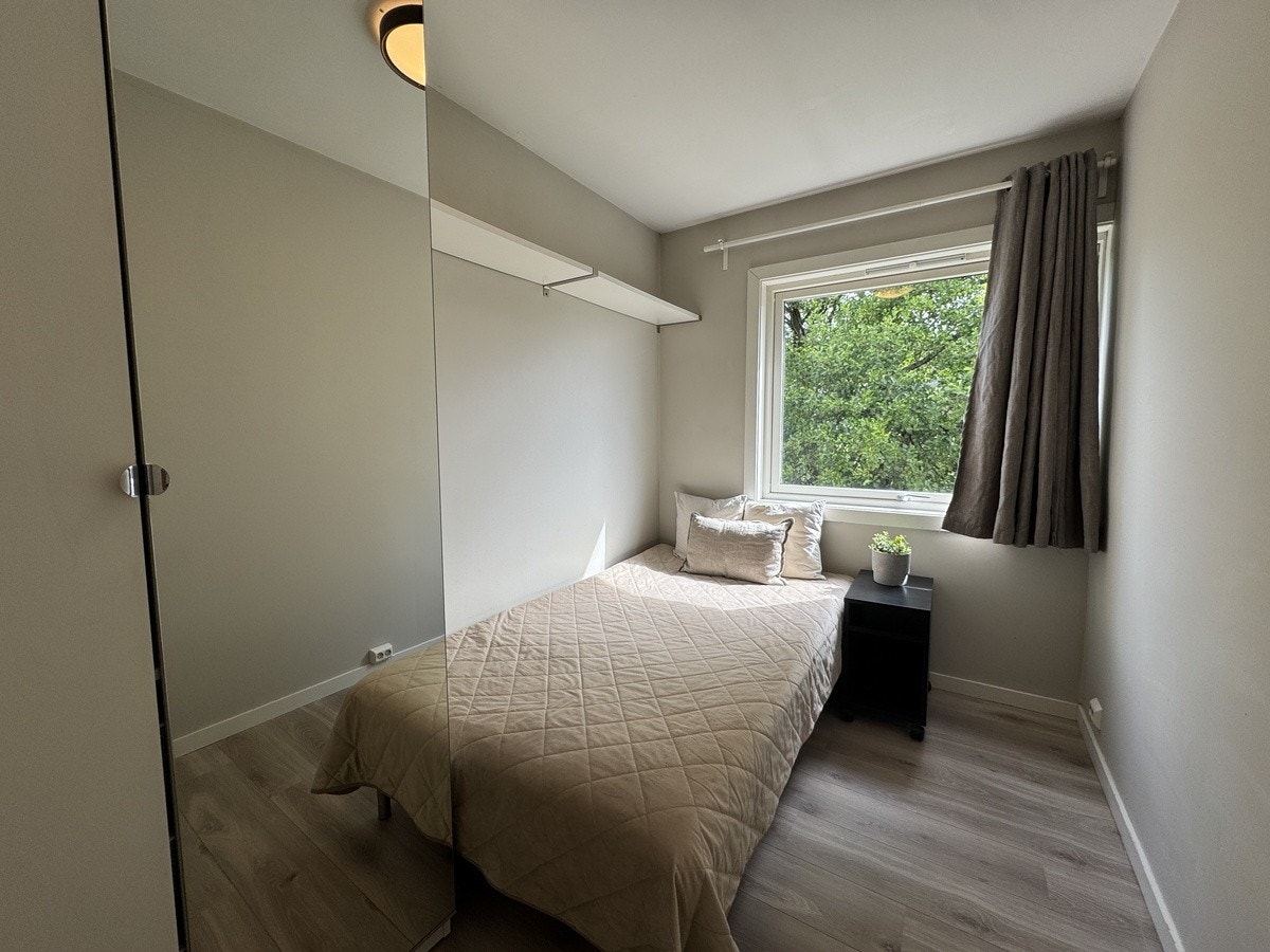 Rom 1 med 120cm seng, nattbord og hyller på vegg. Mulighet for å sette inn pult under vindu der nattbord står Galleribilde