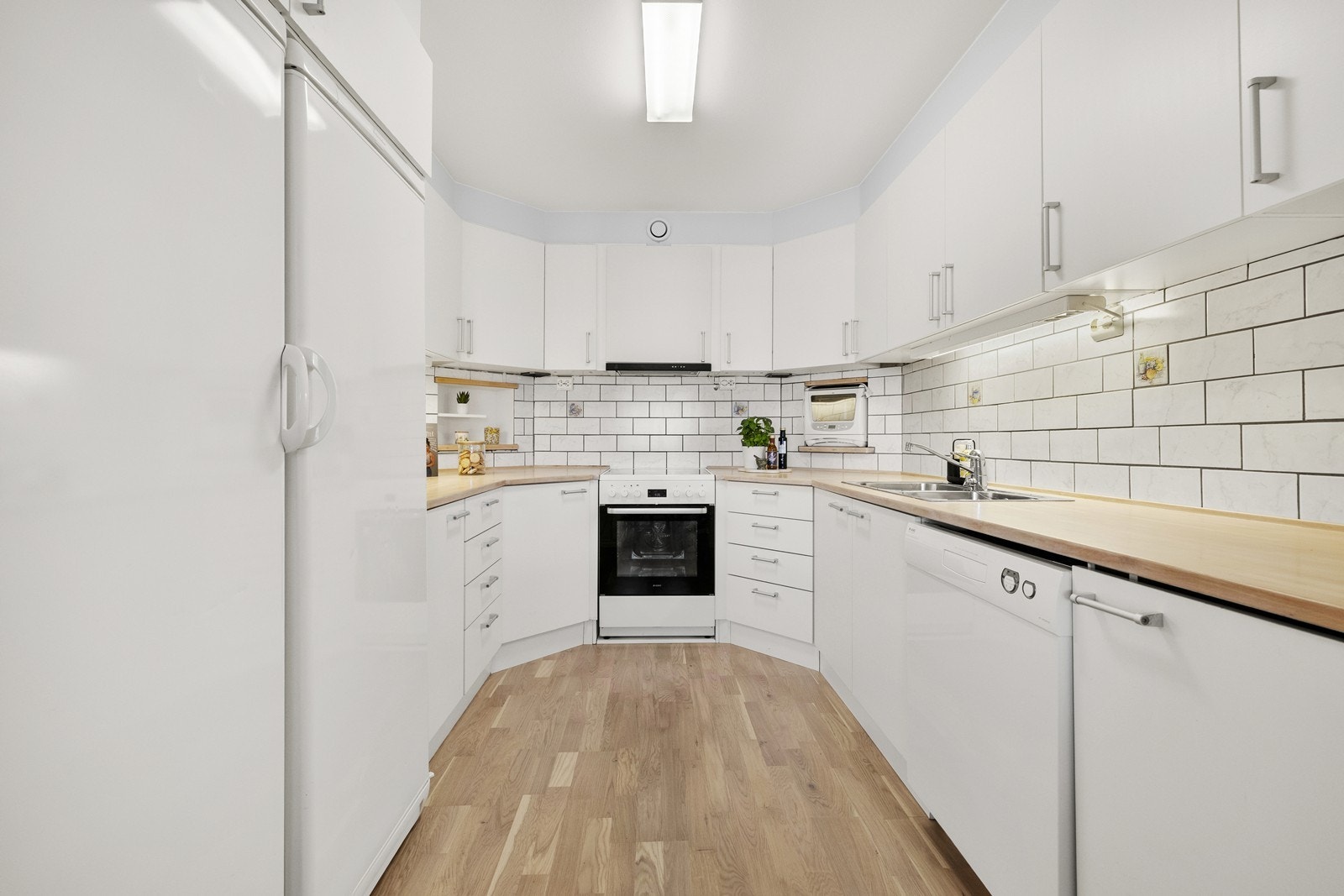 Lyst kjøkken med generelt god plass med mye benkeplate og over- og underskap. Galleribilde