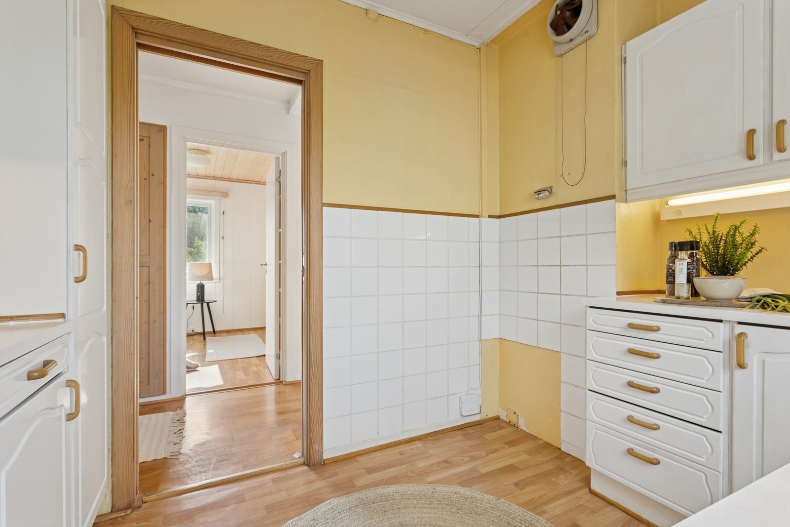 Kjøkkenet har belegg på vegg over deler av benk. Opplegg for oppvaskmaskin, kkomfyrvakt og vifte med avtrekk til luftekanal i pipe. Galleribilde