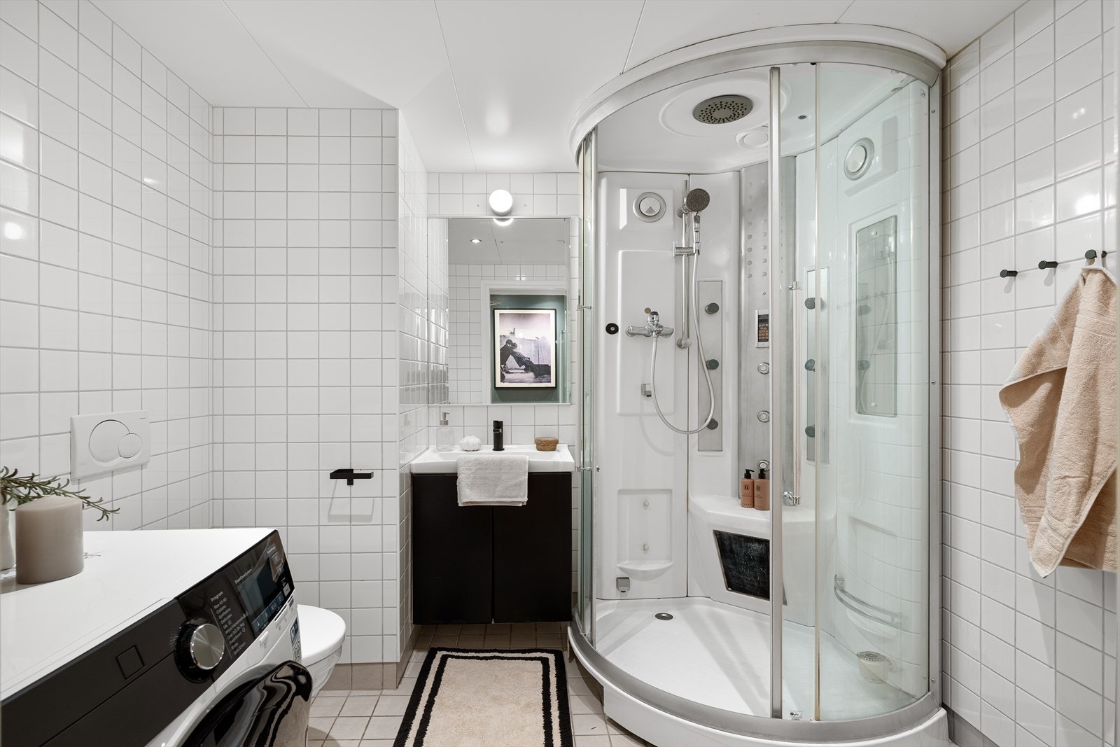 Flislagt bad med dusj, baderomsinnredning, wc og opplegg for vaskemaskin Galleribilde