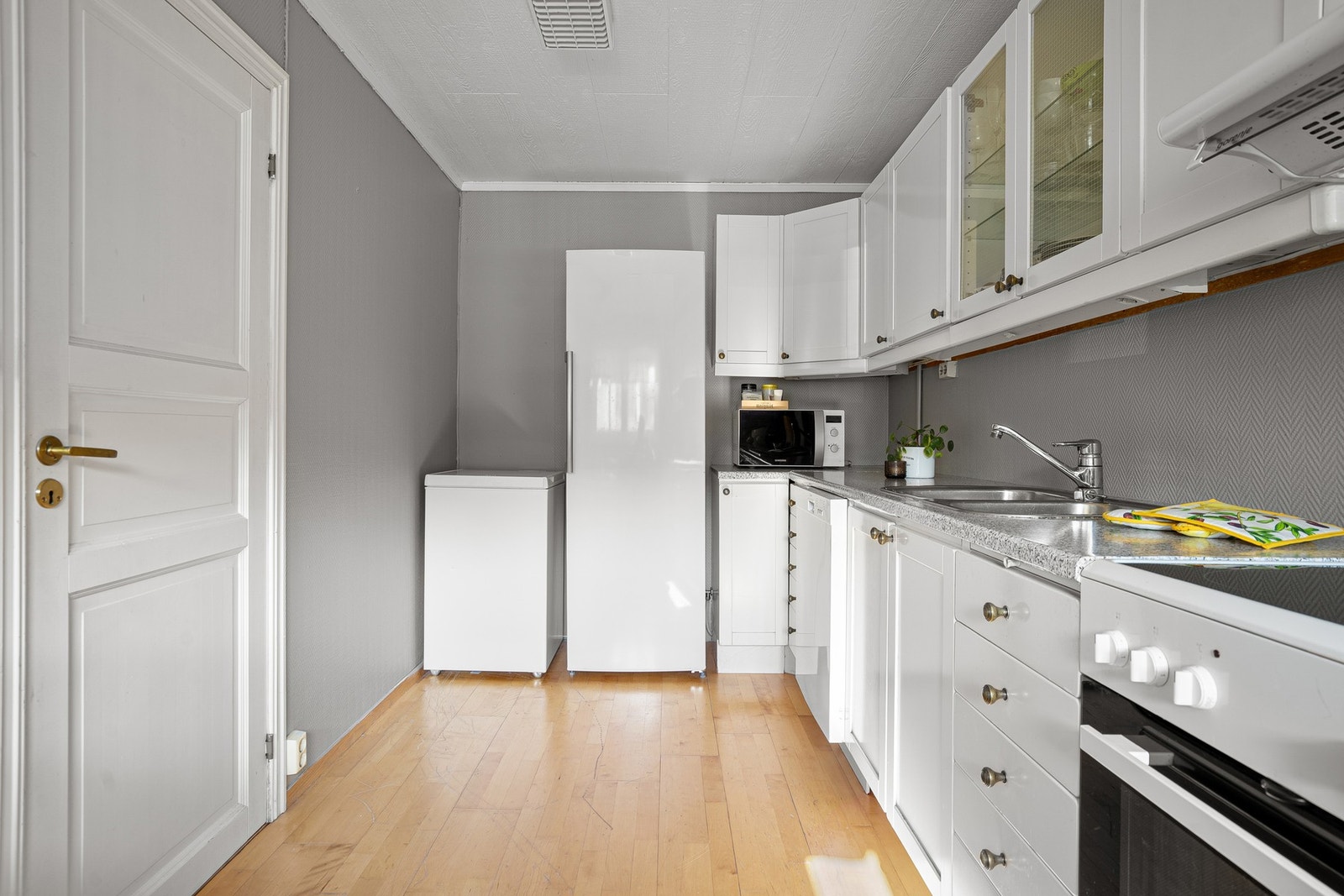 Kjøkkenet består av profilerte over-/underskap, laminert benkeplate, kjøleskap, oppvaskmaskin, helstøpt servant med 2 kummer, komfyr med ventilator over Galleribilde