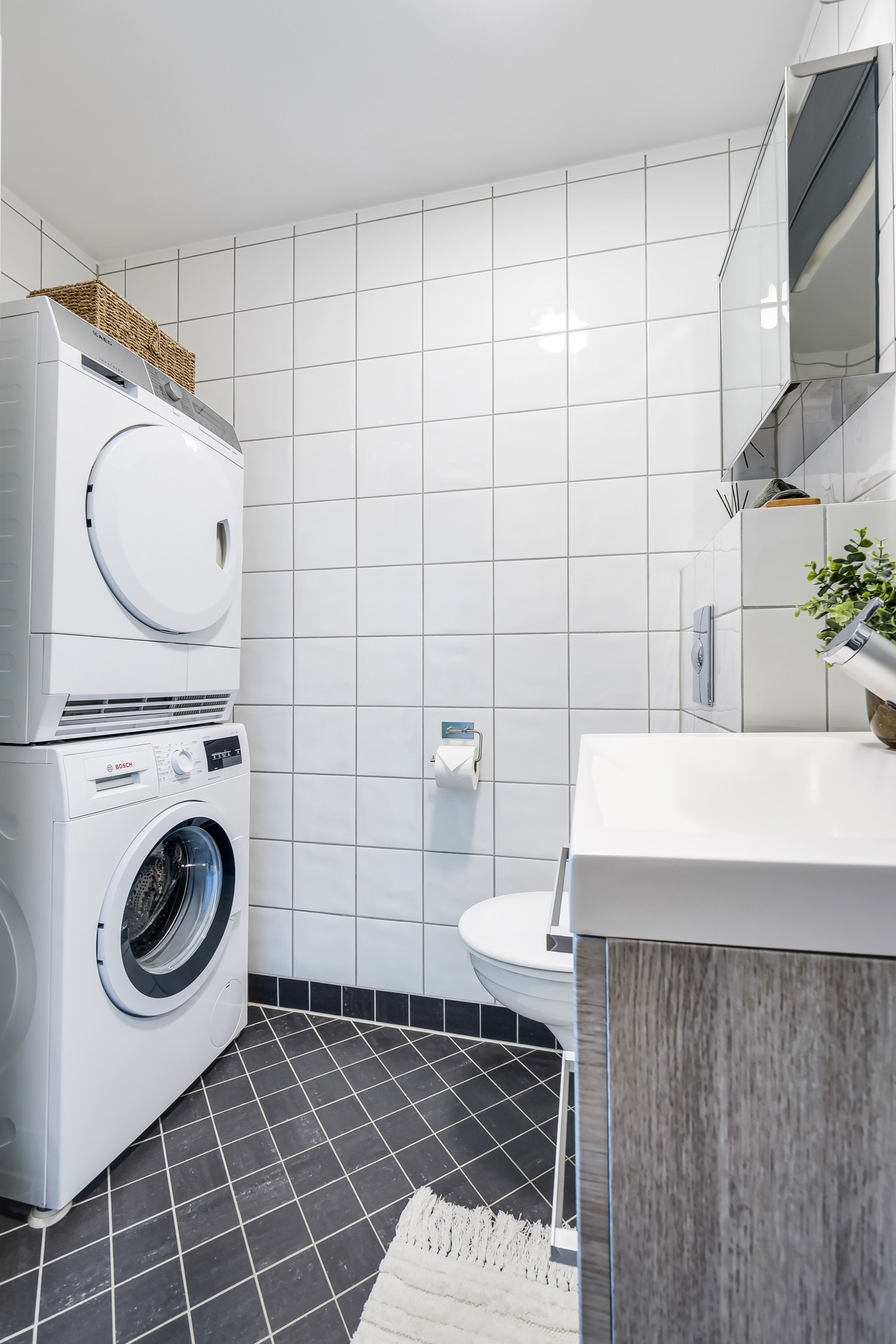 Baderommet har vegghengt servantinnredning med heldekkende servant, speil med belysning, dusjhjørne, vegghengt toalett og opplegg for vaskemaskin og tørketrommel. Galleribilde