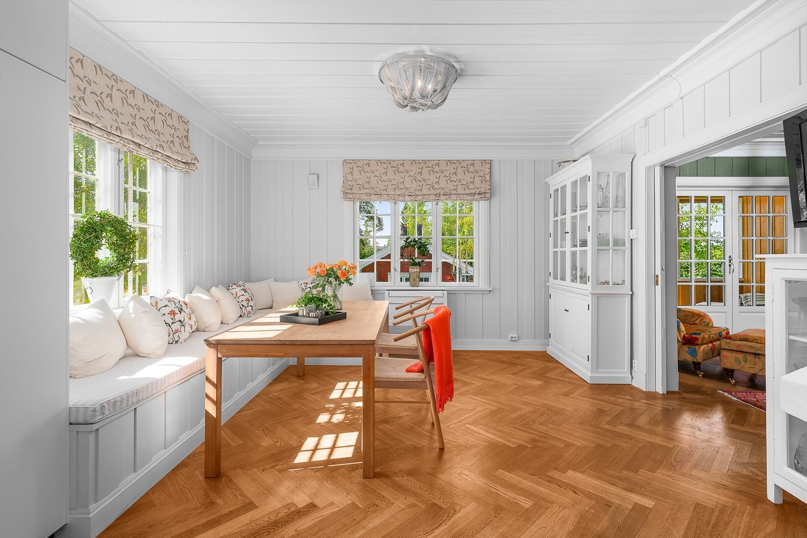 Spiseplass i tilknytning til kjøkkenet med kjøkkensofa, plassbygget av møbelsnekker, bord og stoler som står i god stil med parketten Galleribilde