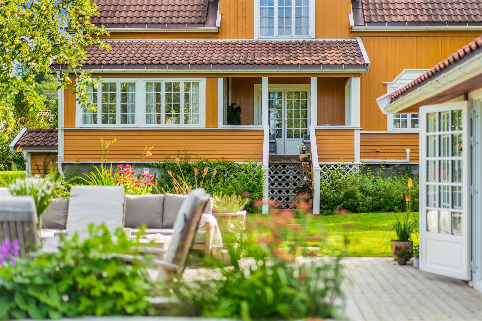 Terrasse i forkant av hagestue med blomsterkasser rundt. Adkomst fra huset med skiferheller Galleribilde