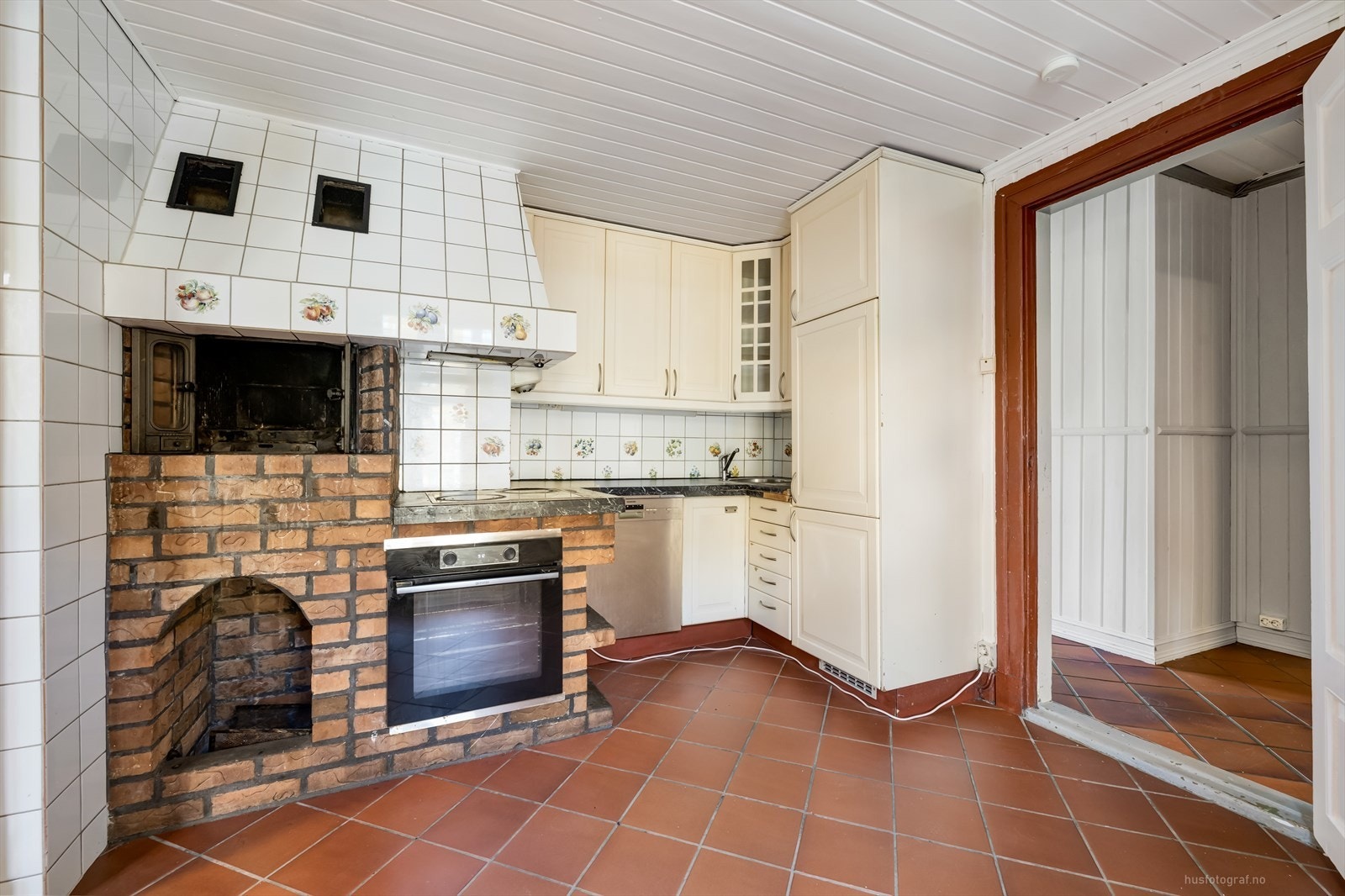 Kjøkken med vedovn samt kjøleskap, fryseskap, oppvaskmaskin, stekeovn og keramisk topp. Galleribilde
