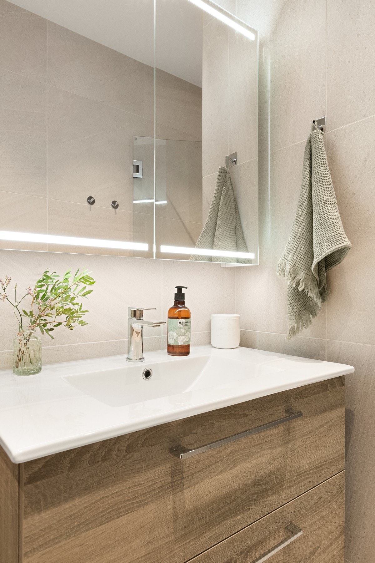 Store, beige fliser gir rommet et sofistikert uttrykk, mens innredningen er nøye utformet for å kombinere funksjonalitet med stilfullt design. Galleribilde