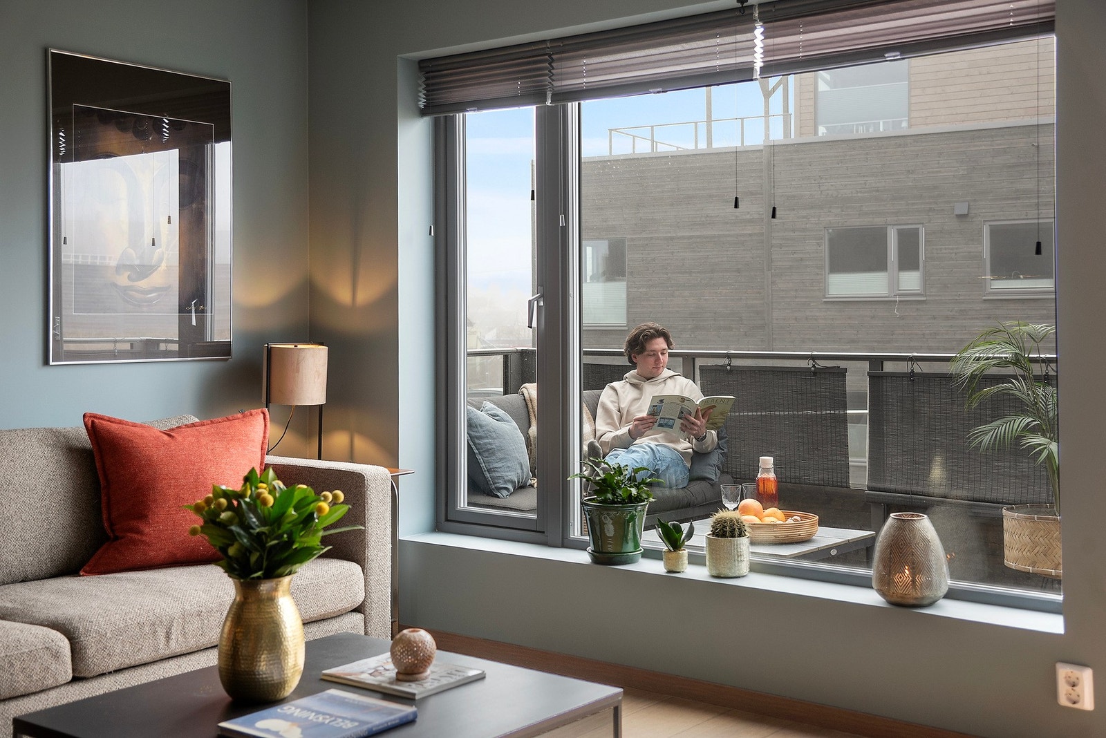 Stuen bades i dagslys fra store vinduer og har utgang til en stor terrasse med ettermiddagssol Galleribilde