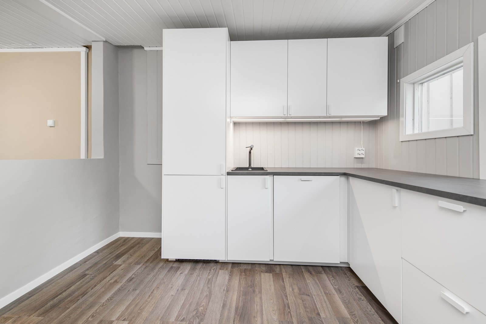 Innredningen har lyse slette fronter. Laminerte benkeplater med nedfelt oppvaskkum i svart kompositt, Galleribilde