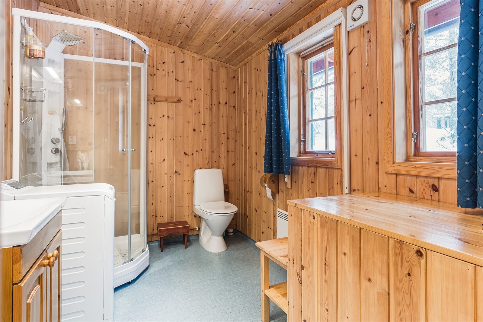 Velholdt og romslig baderom med belegg på gulv, overflater med panel, to vinduer og mekanisk avtrekk. Galleribilde