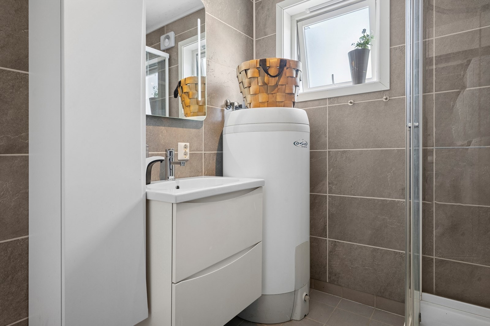 Innredningen består av speil, servant med seksjon, veggmontert skap, veggmontert toalett, dusjkabinett og opplegg for vaskemaskin. Galleribilde