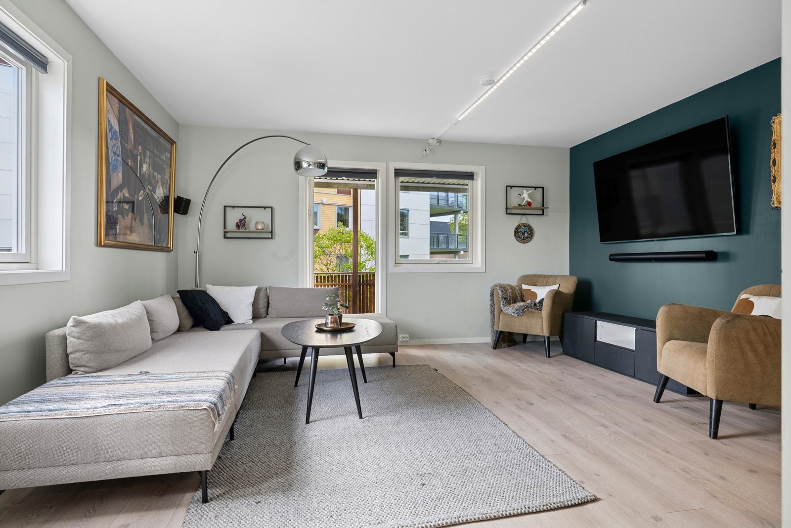 Leilighetens oppholdsrom har en åpen løsning som kombinerer stue og kjøkken på en funksjonell måte. Stue har laminatgulv og malte vegger. Galleribilde