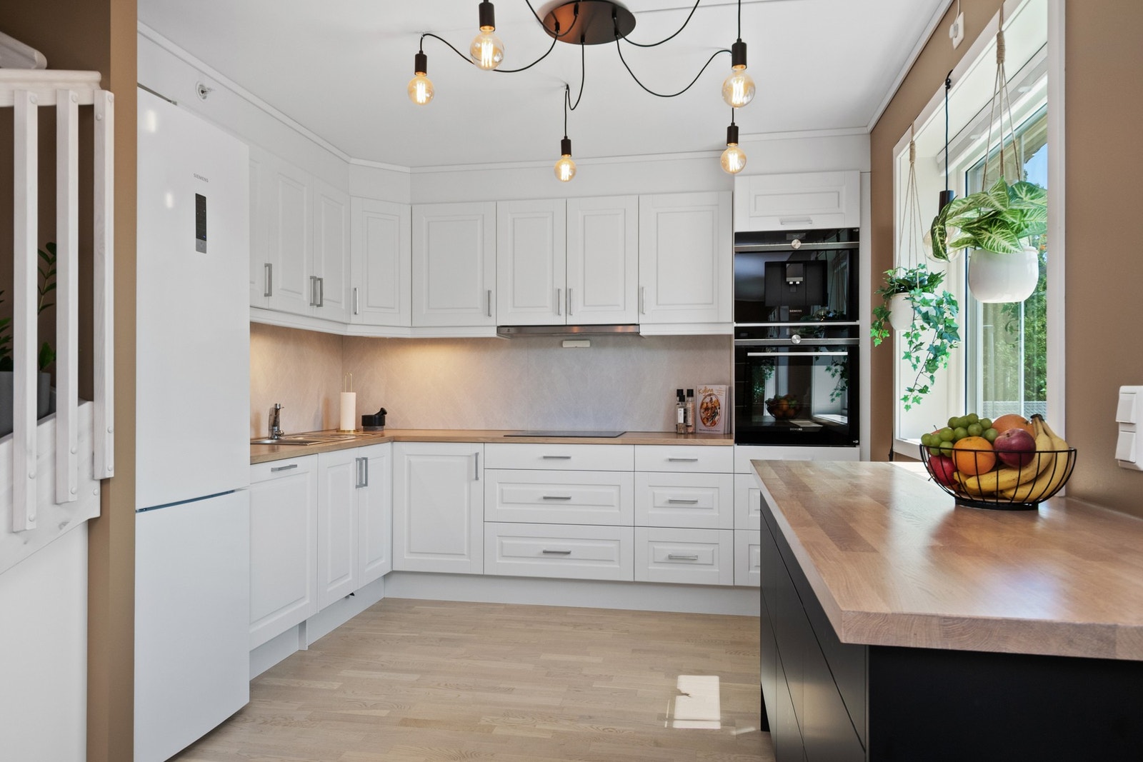 Kjøkkenet har klassisk, hvit innredning med profilerte fronter og benkeplater i heltre Galleribilde