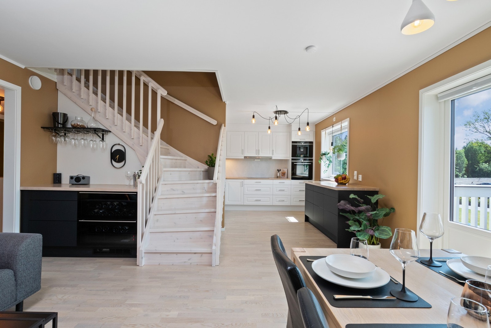 Den sorte innredningen videreføres inn i stuen, hvor to integrerte vinskap danner et lekkert, lite barhjørne - perfekt for både hverdag og gjester. Galleribilde