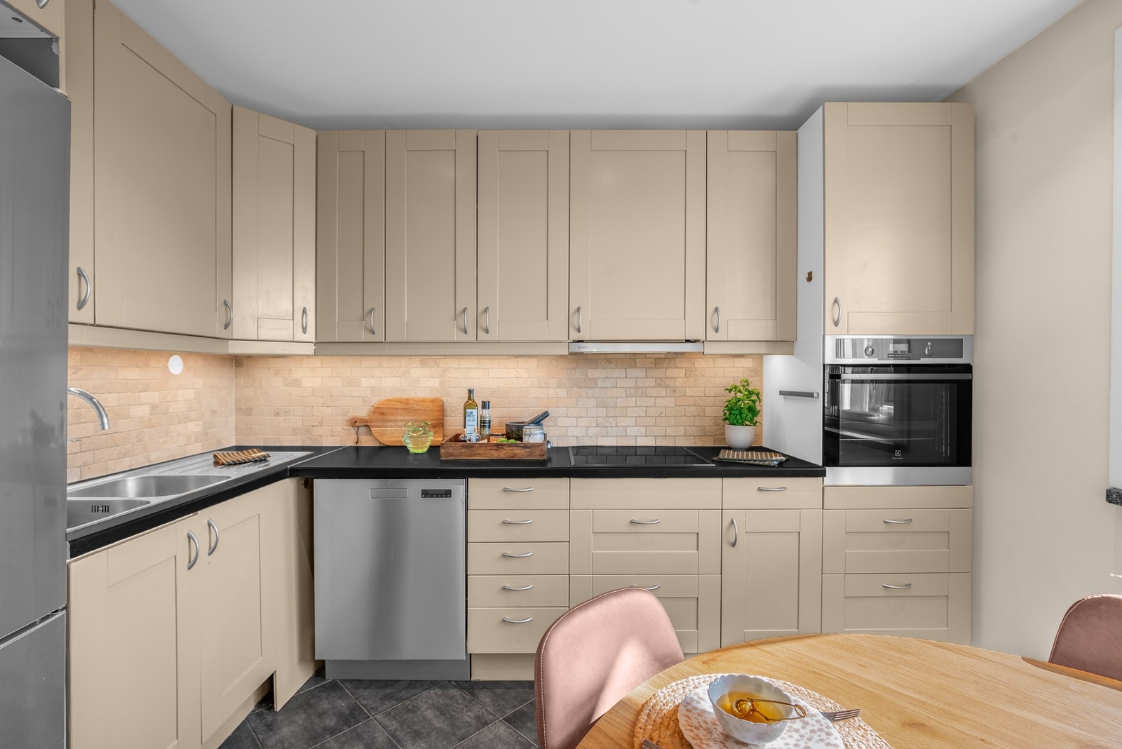 Det er integrert platetopp og stekeovn, opplegg for oppvaskmaskin, samt plass til kjøle- og fryseskap. Over benken er det fliser og belysning under overskapene som gir god arbeidsbelysning Galleribilde