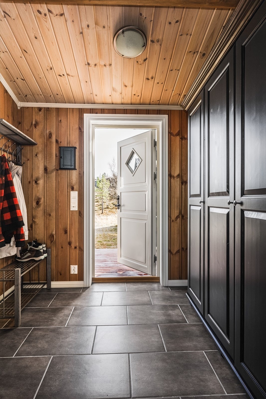 Når du entrer hytta kommer du inn i en innbydende og praktisk entré. Entréen har mørke fliser på gulv med gulvvarme, overflater med lun panel og skjult elektrisk anlegg. Galleribilde