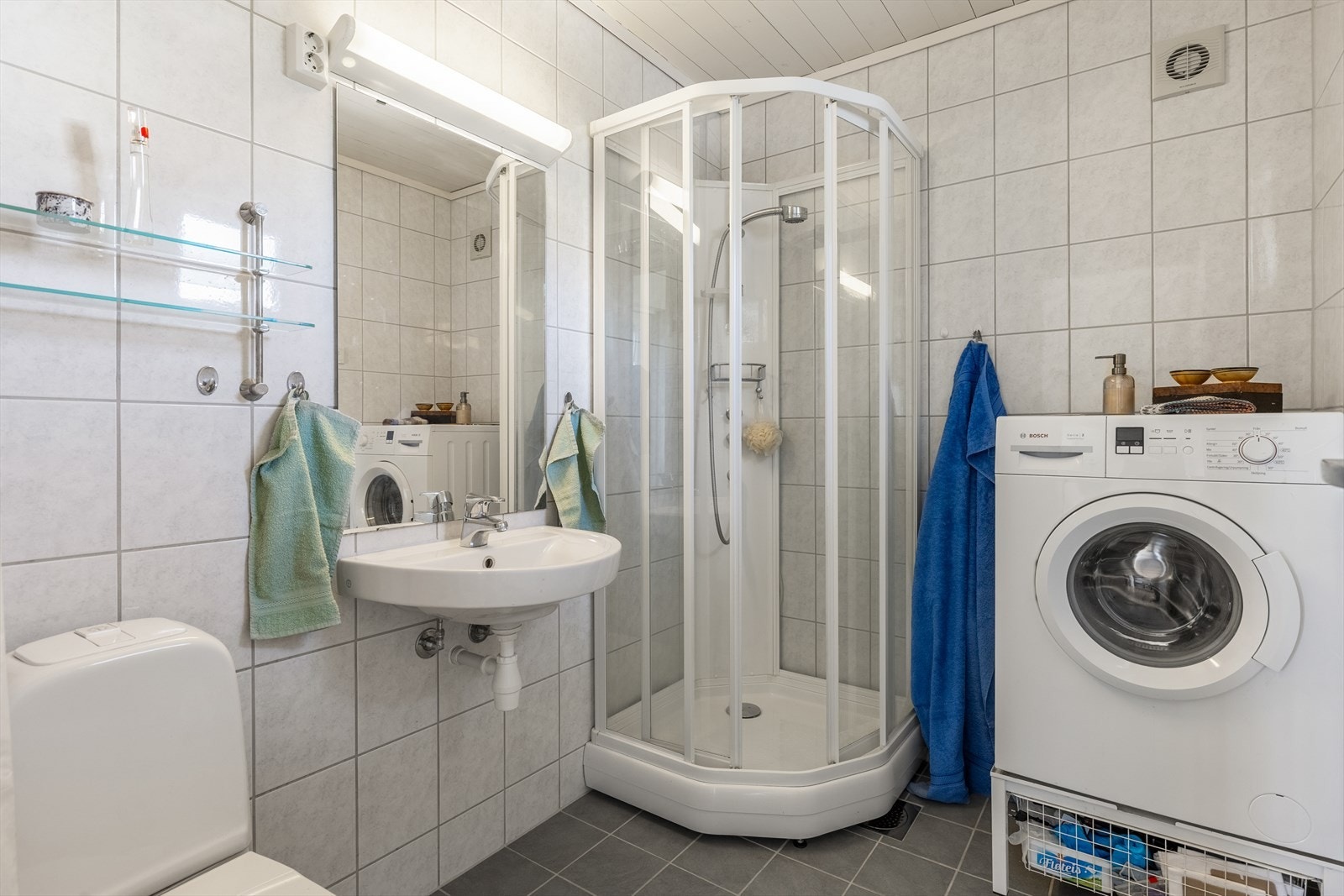 Kombinert bad/vaskerom fra byggeår. Veggflatene er utført med fliser og det er benyttet malt trepanel i tak / himlingen. Flislagt gulv. Våtrommet er utført med elektrisk gulvvarme Galleribilde