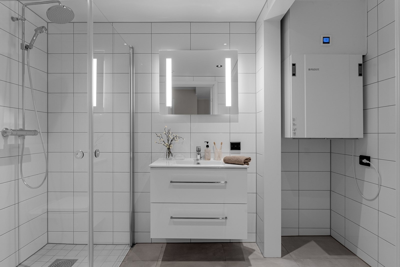 Badet fremstår som arealeffektivt med pen baderomsinnredning i hvit utførelse. Opplegg for vaskemaskin og tørketrommel kan også nevnes. Galleribilde