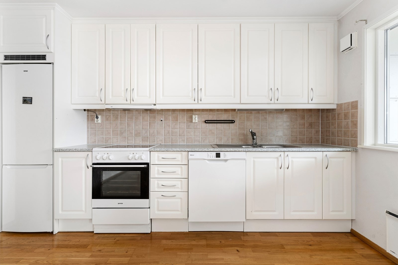 Kjøkkeninnredning i laminat utførelse med profilerte laminerte fronter. Merk deg kjøkkenskapene som går helt opp til tak. Fliser på vegg mellom over- og under skap. Galleribilde