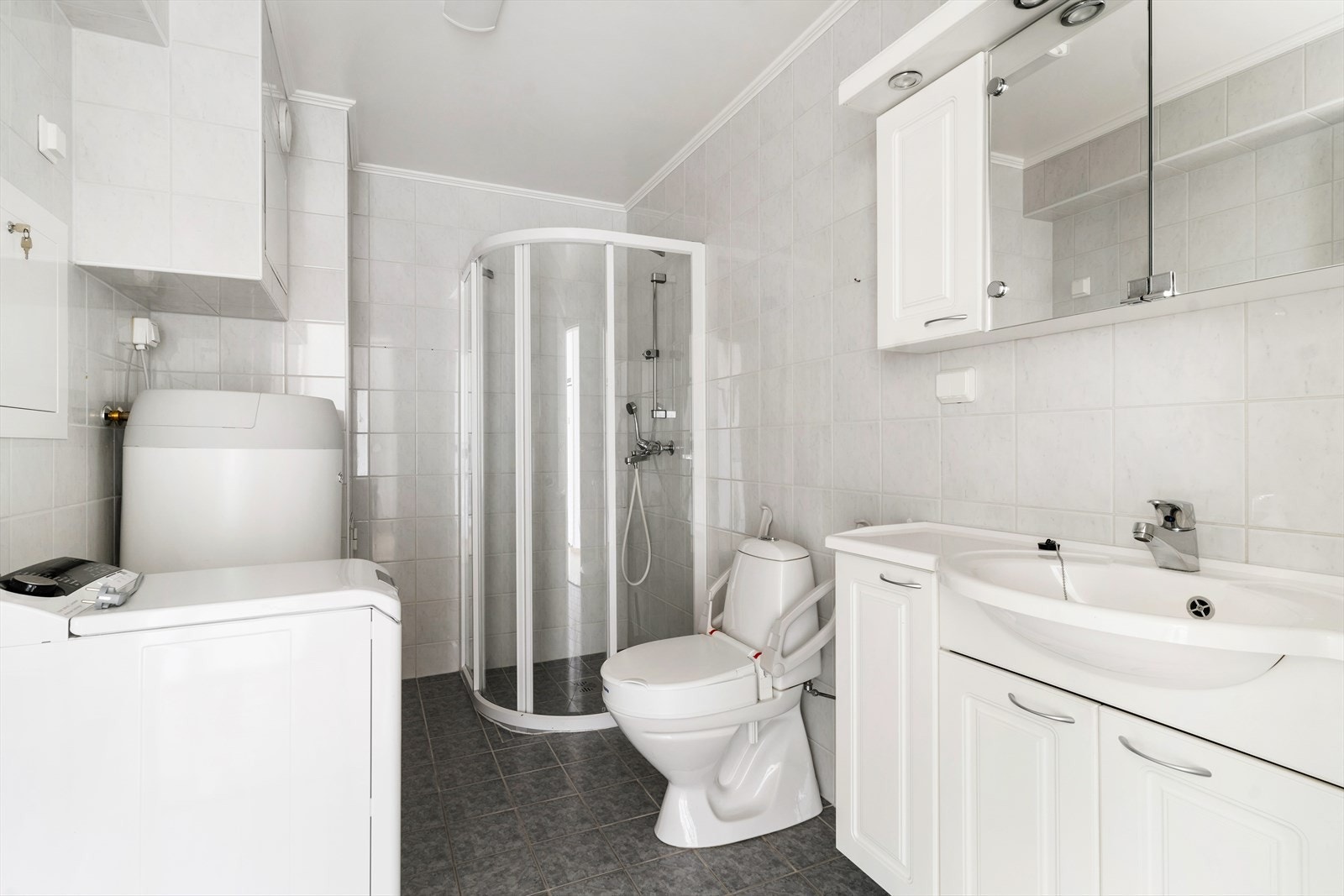 Badet er flislagt og har opplegg for vaskemaskin. Godt med skapplass i innredningen samt spotter på toppen av overskapene. Galleribilde