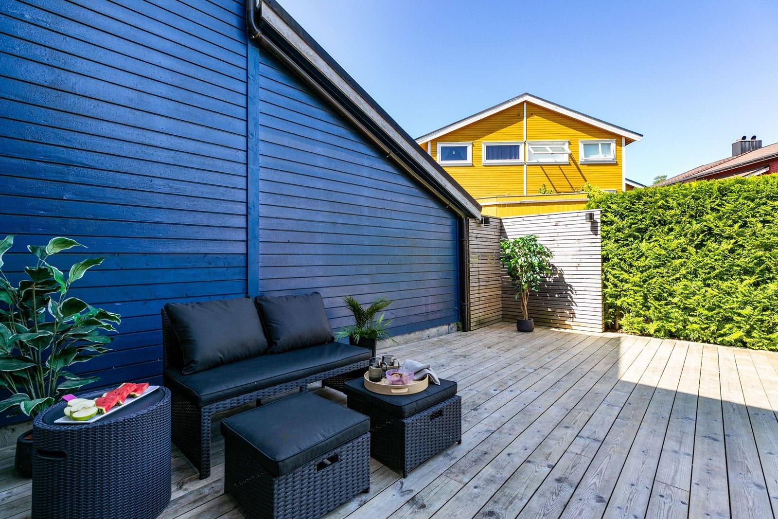 Foran inngangspartiet er det kveldssol sommerstid. Høy og tettvoksende hekk hindrer innsyn fra gaten. Galleribilde