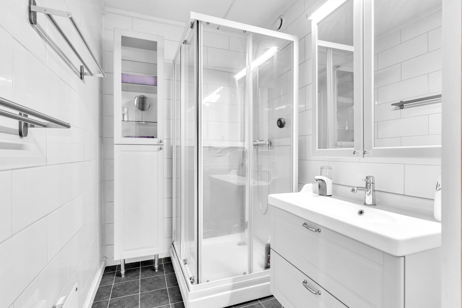 Badet er innredet med dusj, servant og to veggskap med speil og belysning. Galleribilde