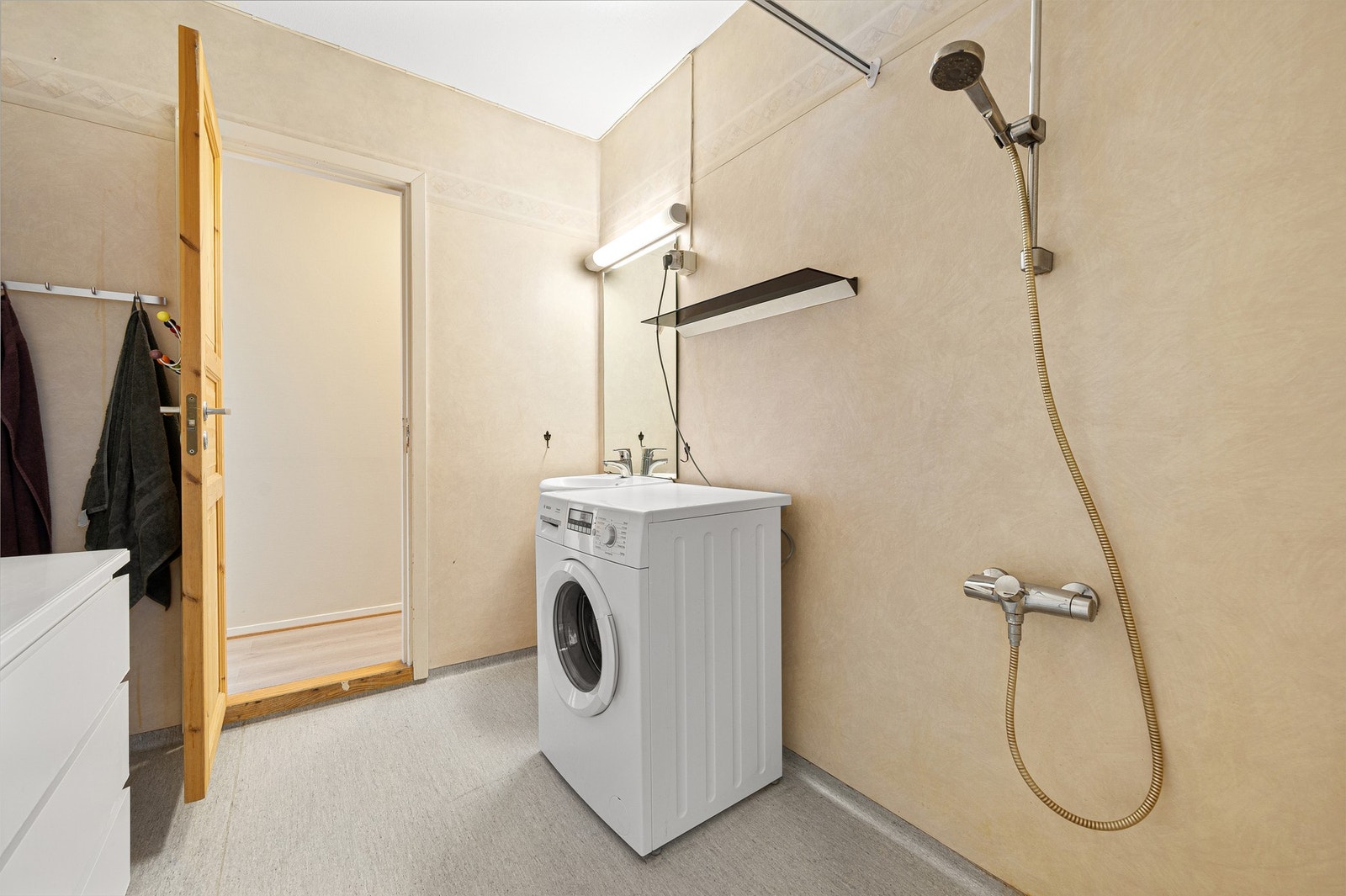 Bad utstyrt med dusjforheng med dusjgarnityr, servant t og opplegg for vaskemaskin. Galleribilde