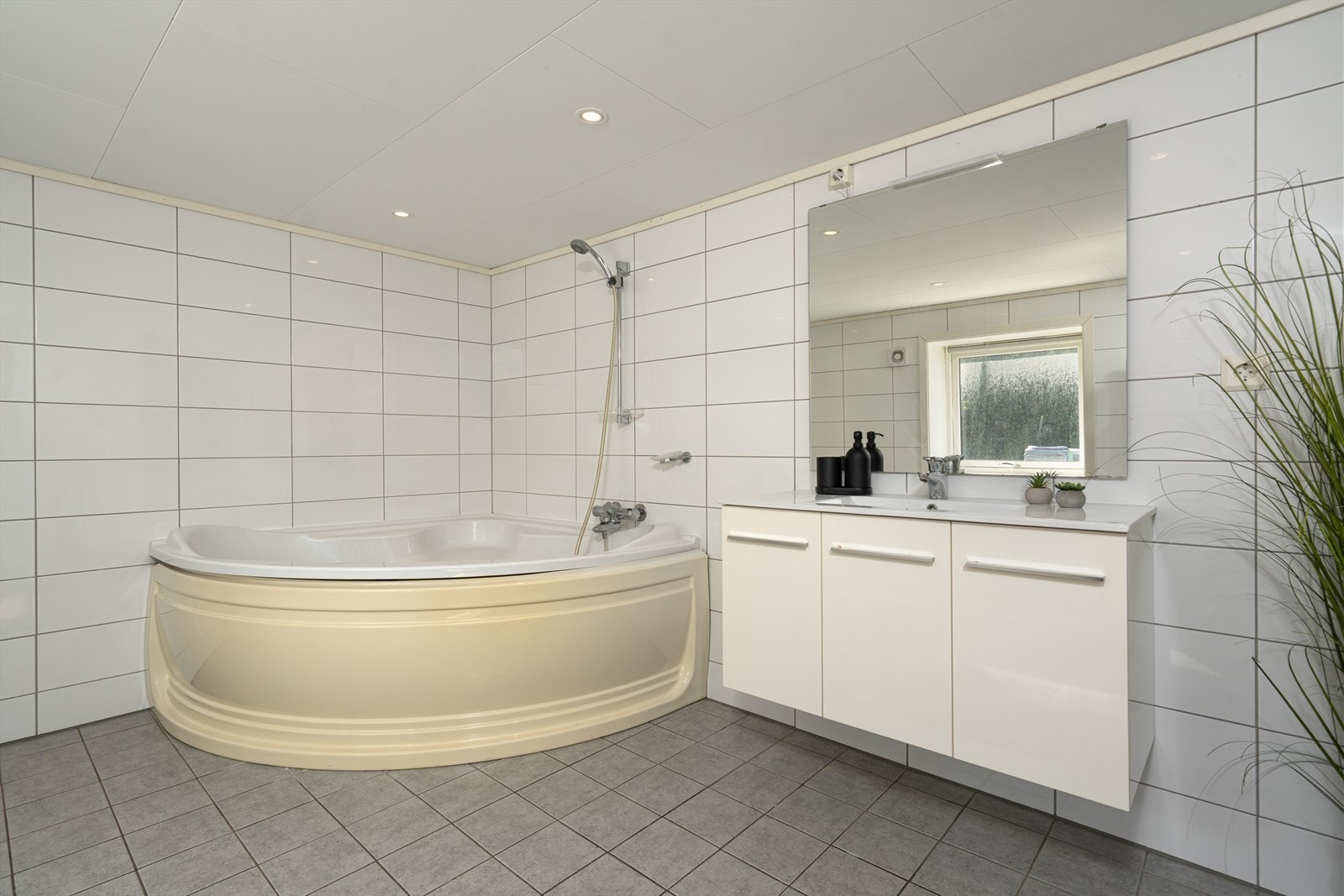 Flislagt baderom med dusj, badekar, toalett, baderomsmøbel med heldekkende servant samt opplegg for vaskemaskin. Varmekabler i gulv. Mekanisk avtrekk. Galleribilde