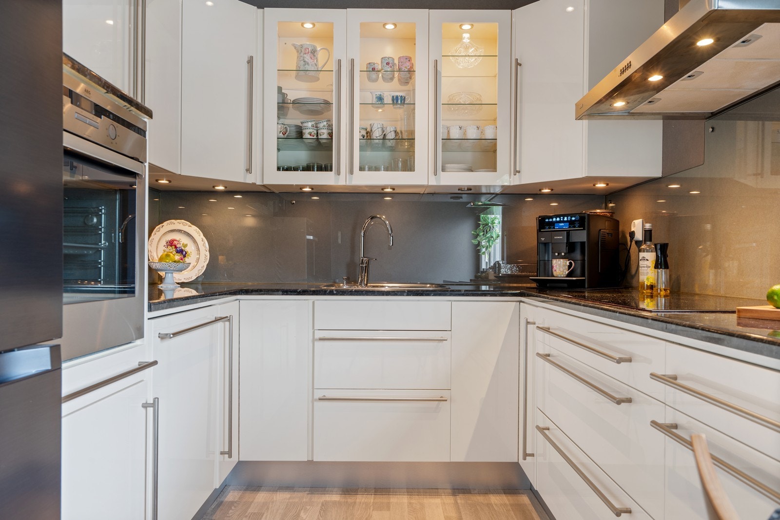 Pen kjøkkeninnredning i merket Drømmekjøkken. Downlight belysning i og under overskap. Induksjonstopp, integrert komfyr, oppvaskmaskin og frittstående kjøleskap (medfølger). Galleribilde