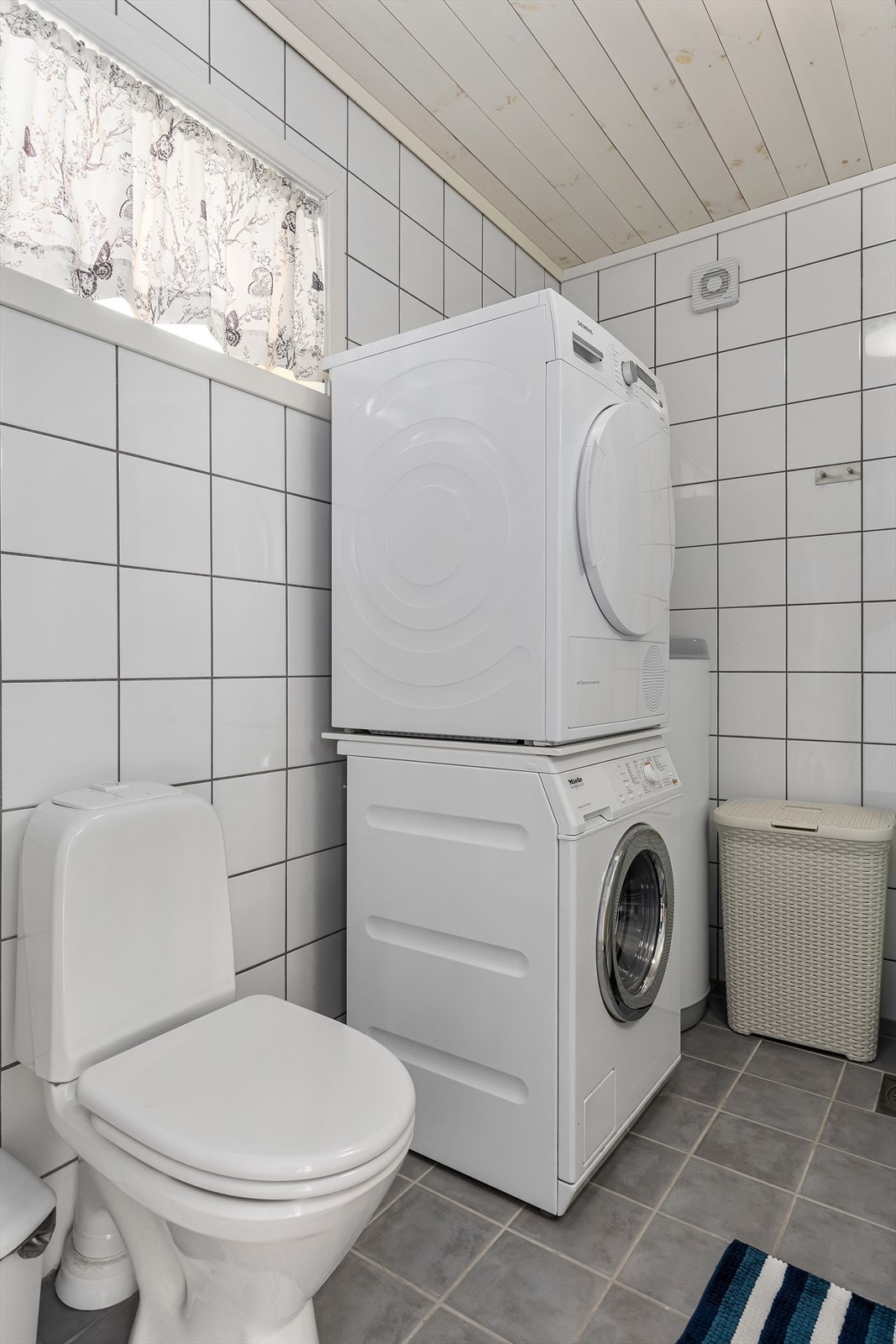 Bad/vaskerom har fliser på gulv og vegger Galleribilde