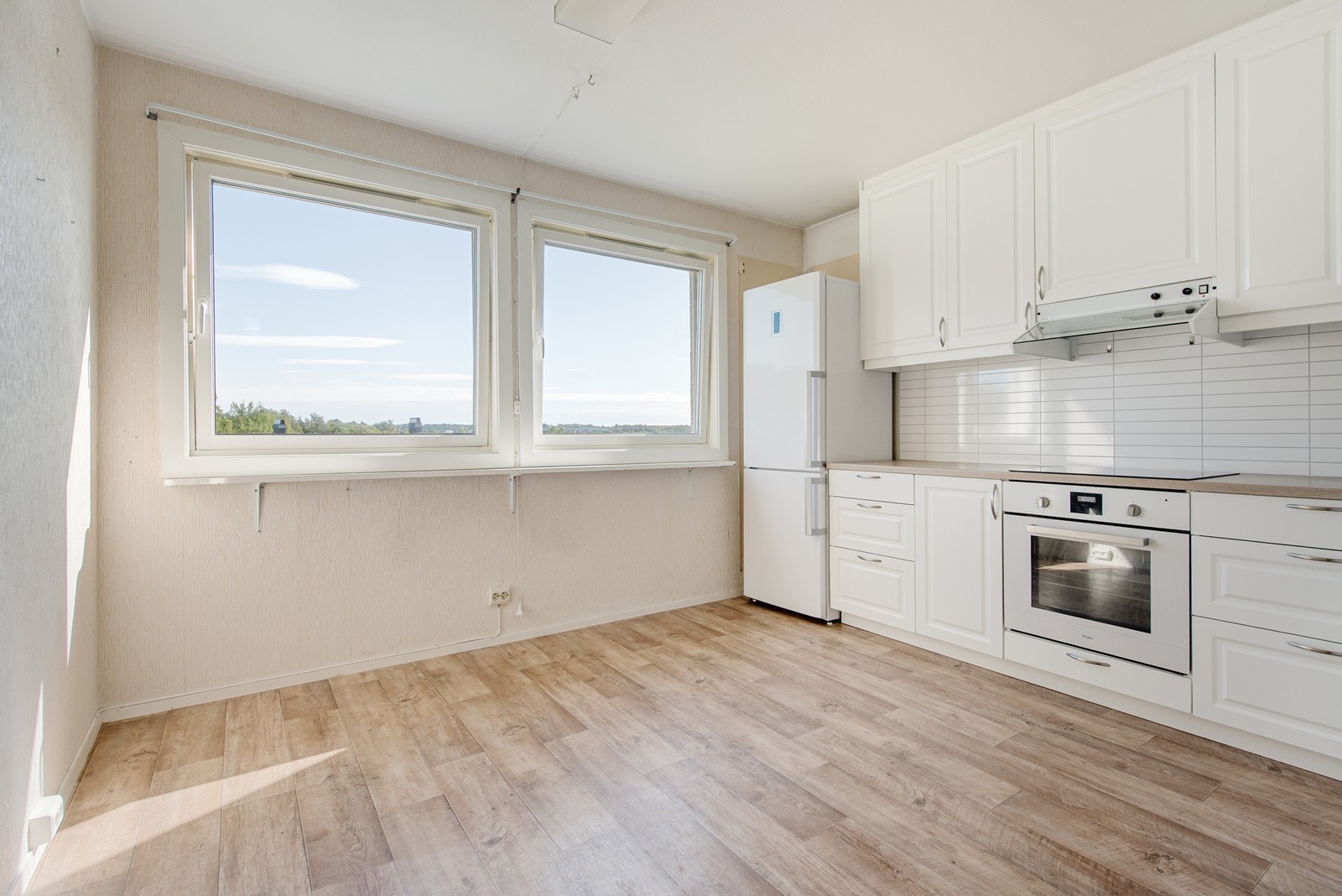 Store vinduer som slipper inn herlig lys på kjøkkenet. en hyggelig plass å ha et lite spisebord. Galleribilde