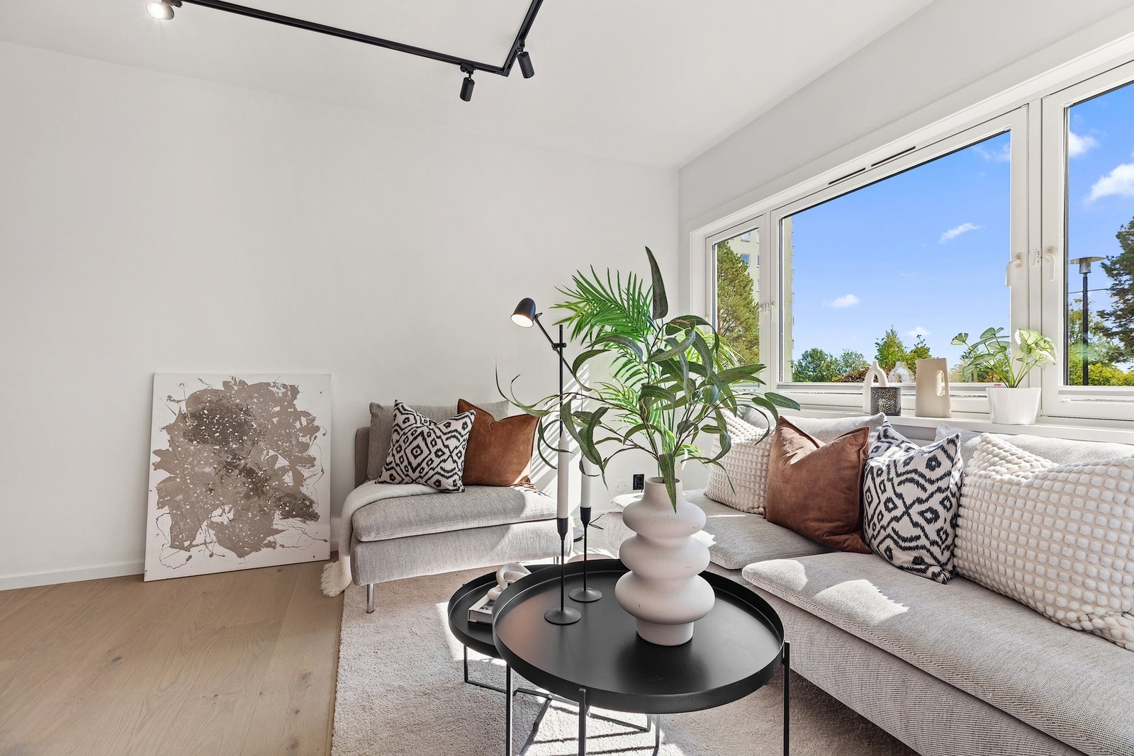 Koselig sofakrok med mye naturlig lys og grønne omgivelser utenfor. Galleribilde