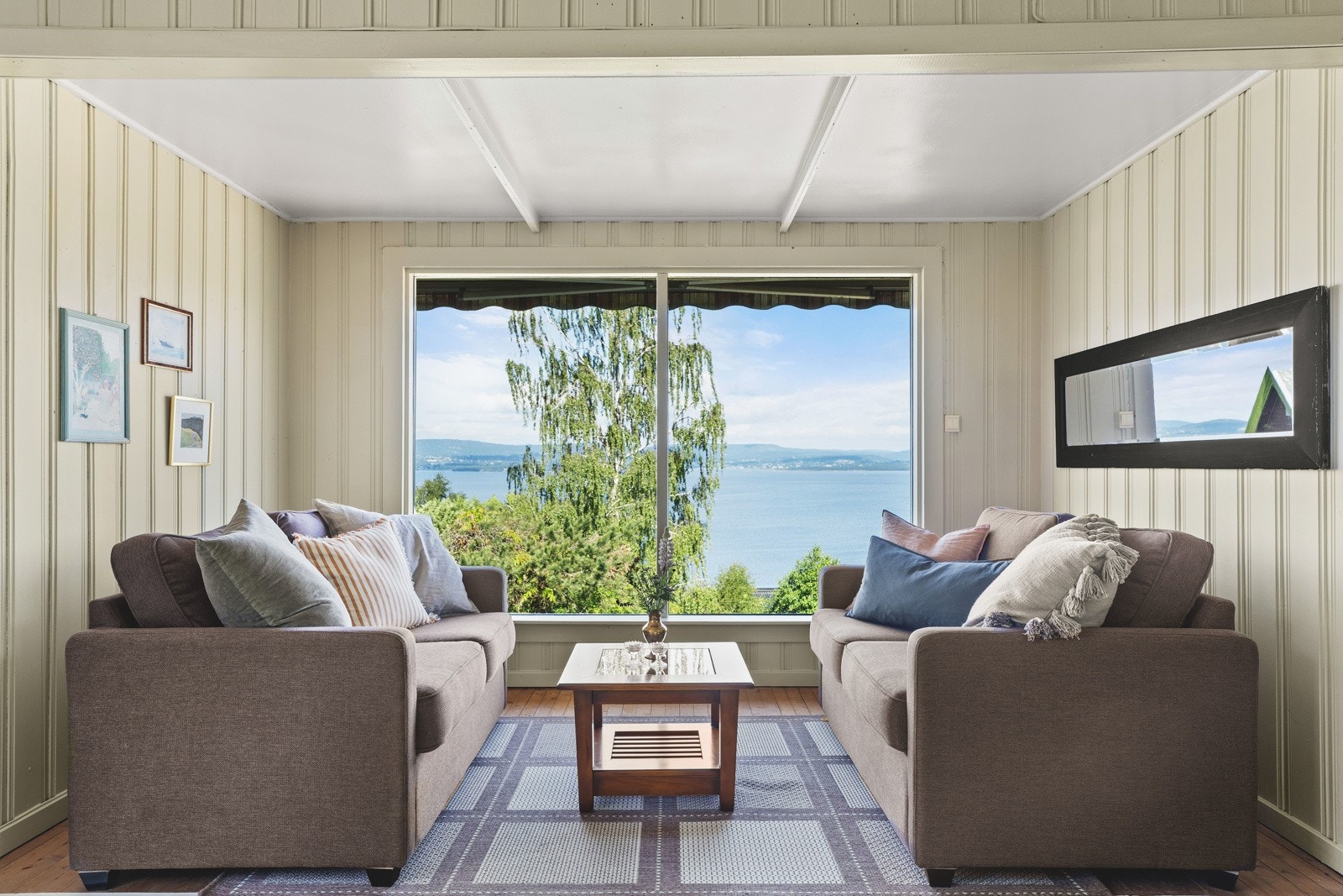 Store vindusflater gir rikelig med naturlig lysinnslipp og man kan sitte i stuen og nyte den fantastiske utsikten Galleribilde