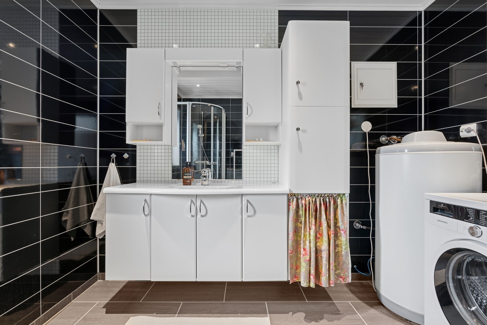 Innredningen består av speil, servant med oppbevaringsseksjon, veggmontert toalett, dusj og opplegg for vaskemaskin. Galleribilde