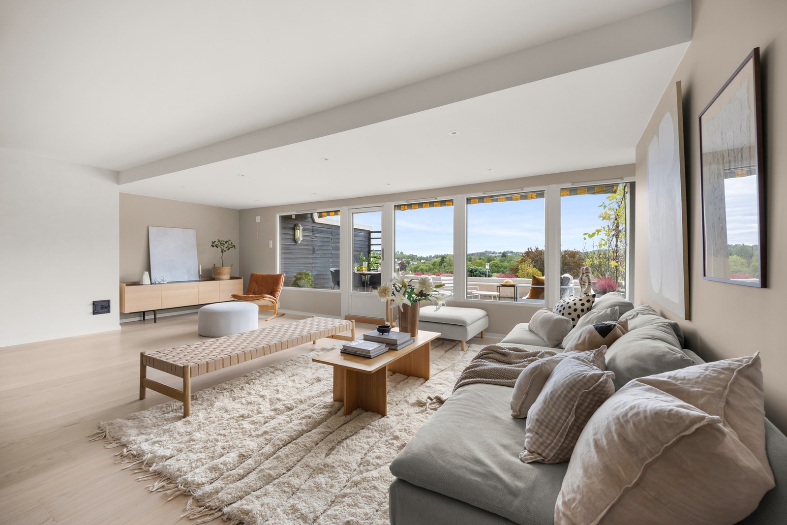 Leilighetens romslige stue byr på store vindusflater som bidrar til en lys og luftig atmosfære Galleribilde