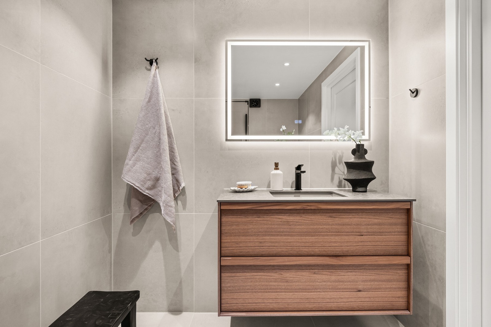 Badet har vegghengt toalett, dusjarmatur og servantinnredning med skuffer Galleribilde