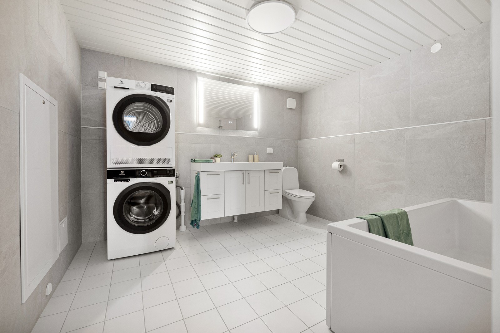 Badet er innredet med servant i baderomsinnredning, badekar, toalett og speil med belysning. Galleribilde