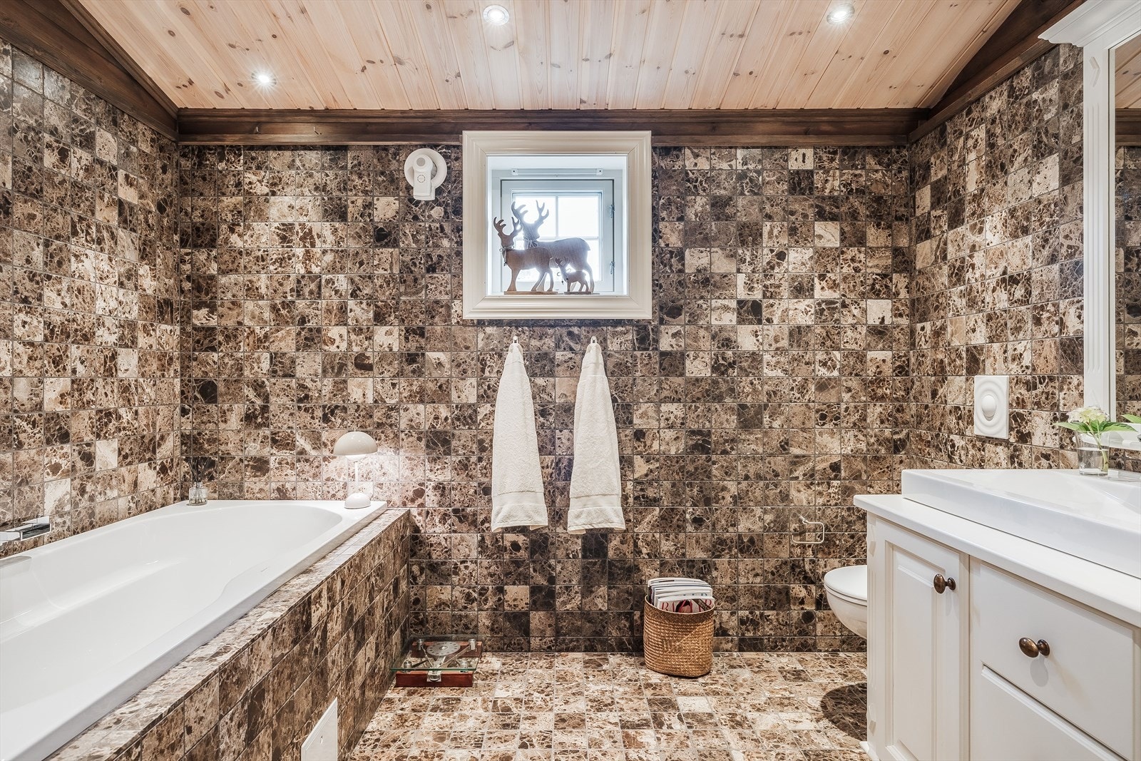 Fritidsboligen har et lekkert og romslig bad med innebygd badekar og avgrenset dusjnisje med glassbyggerstein og dusjdør i glass. Galleribilde