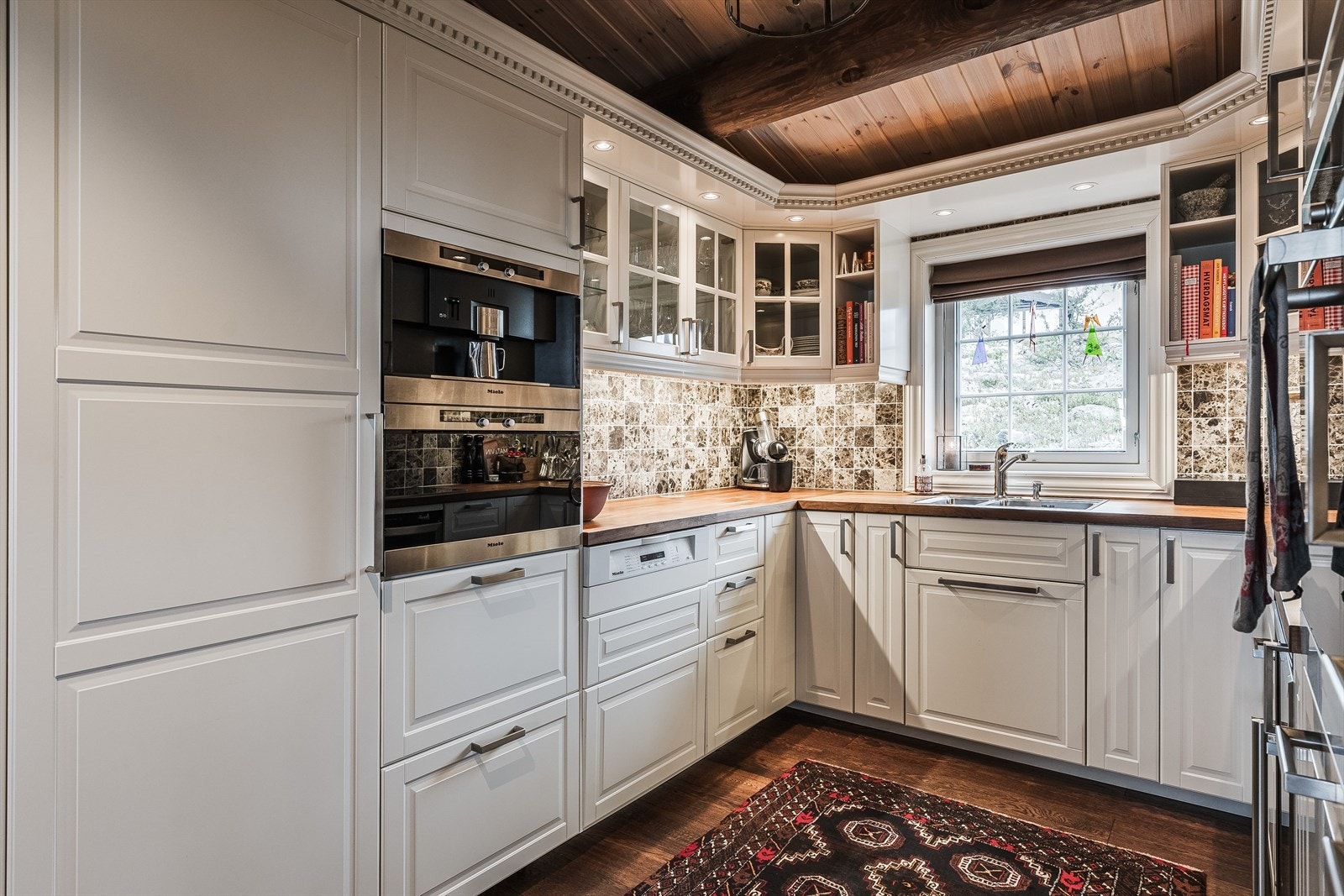 Kjøkkenet er fint innredet i en hesteskoform med hvite og profilerte fronter, finert benkeplate og integrerte hvitevarer som platetopp, komfyr, dampovn, kaffemaskin, oppvaskmaskin og kjøleskap som medfølger. Downlights sørger for god belysning. Galleribilde