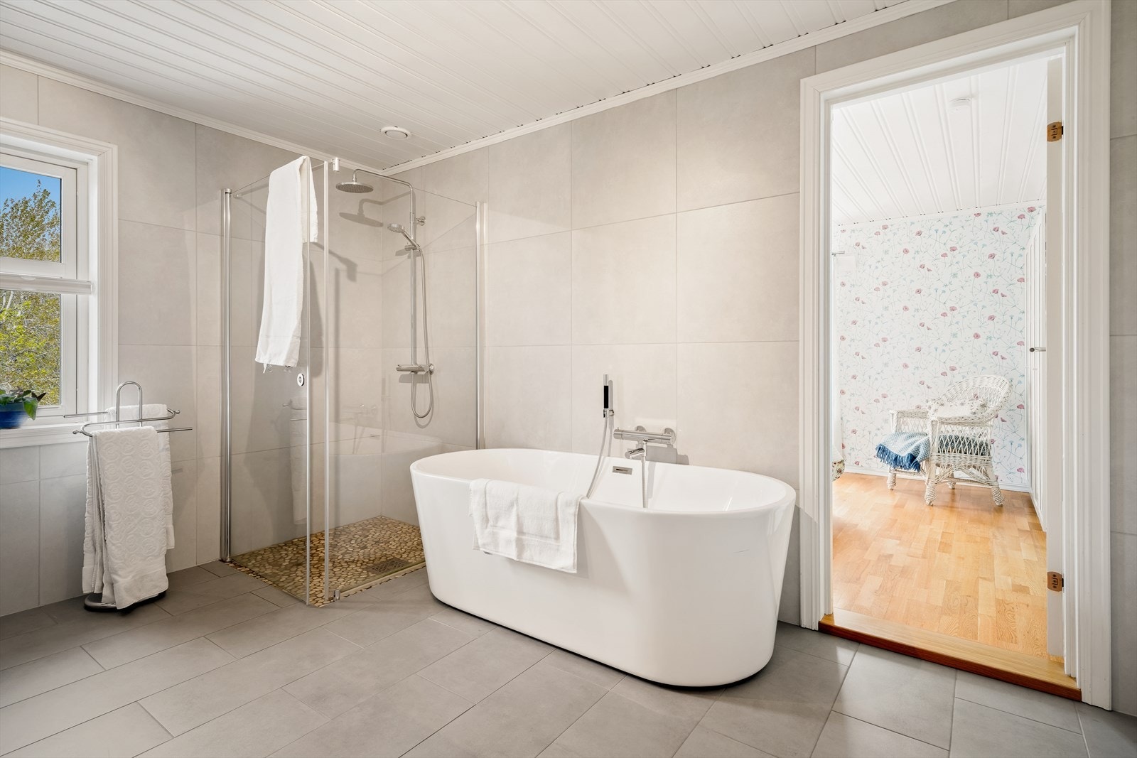 Boligens flotte bad fremstår i en tidløs og moderne stil, med fliser både på gulv og tre av veggene som gir et rent og stilfullt uttrykk. Galleribilde