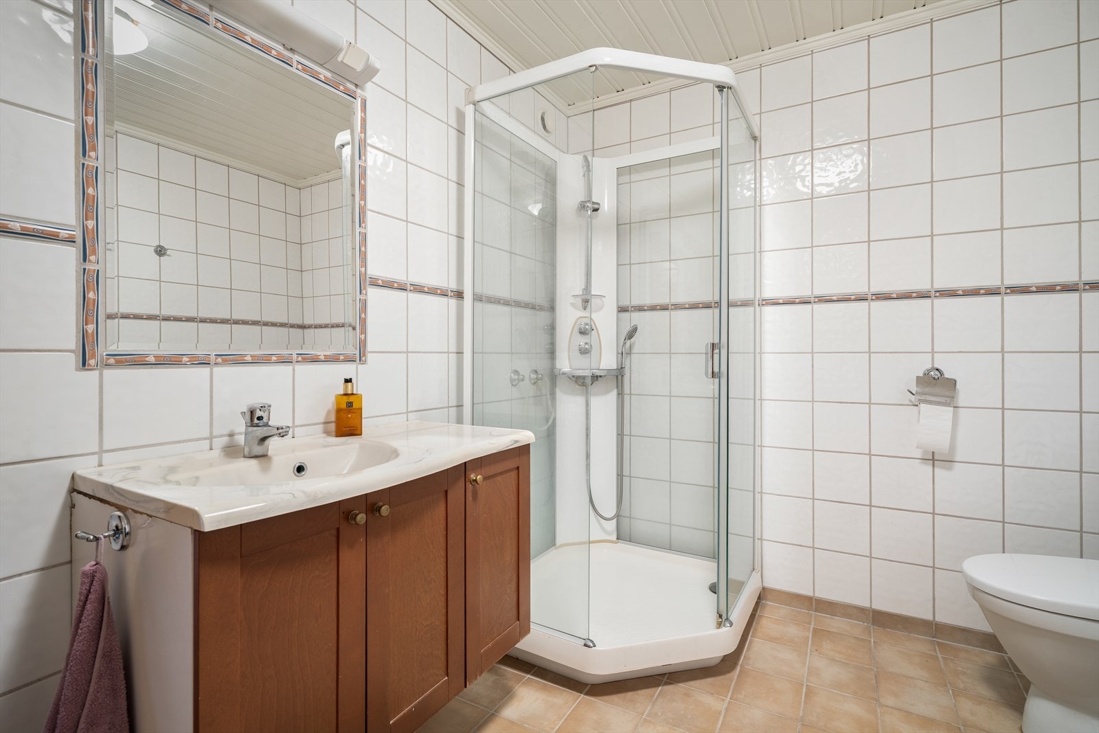 Videre er badet utstyrt med innredning med nedfelt servant, toalett, dusjkabinett og opplegg for vaskemaskin. Galleribilde