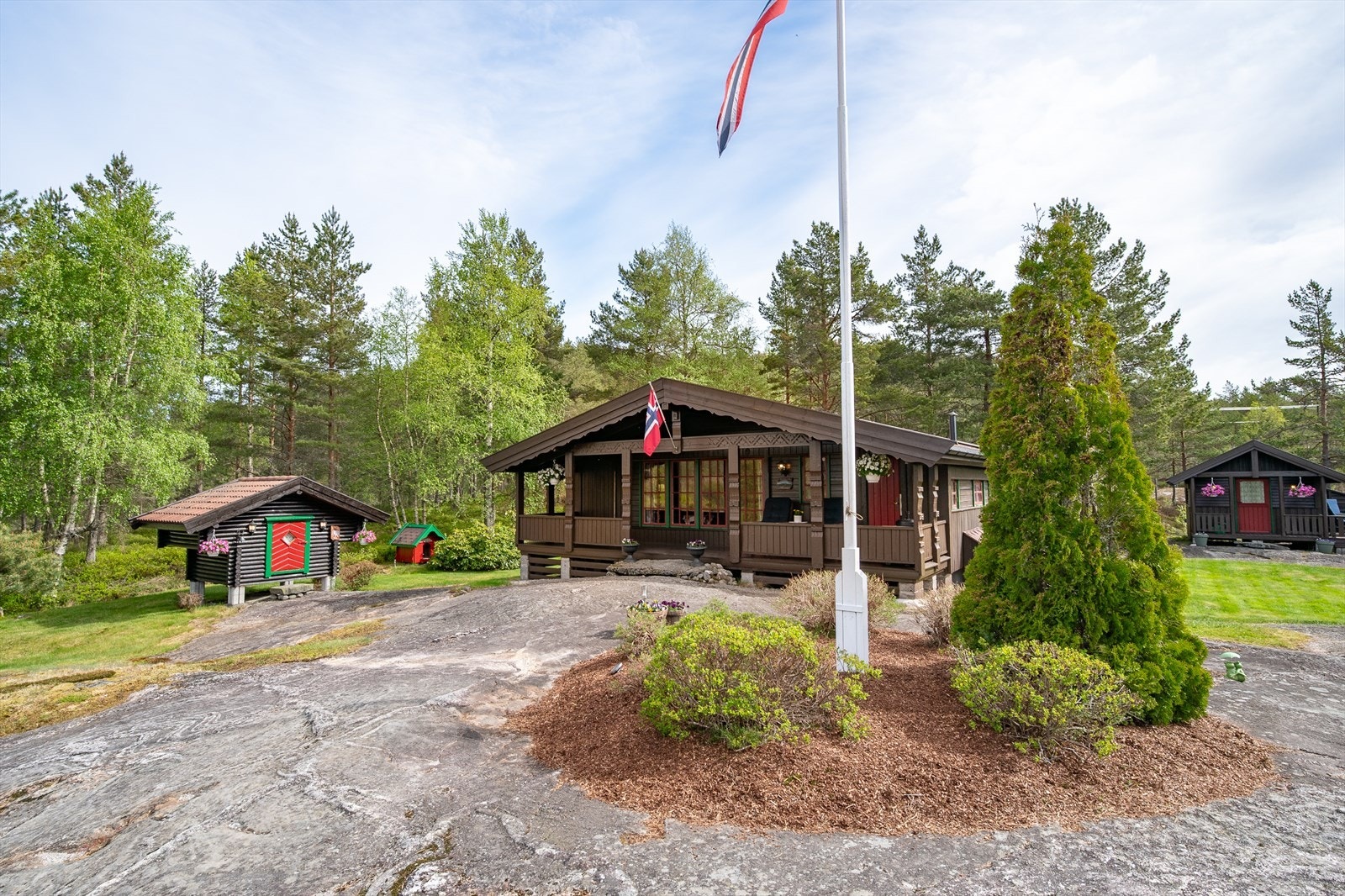 Velstelt eiendom med blomsterbed og flaggstang Galleribilde