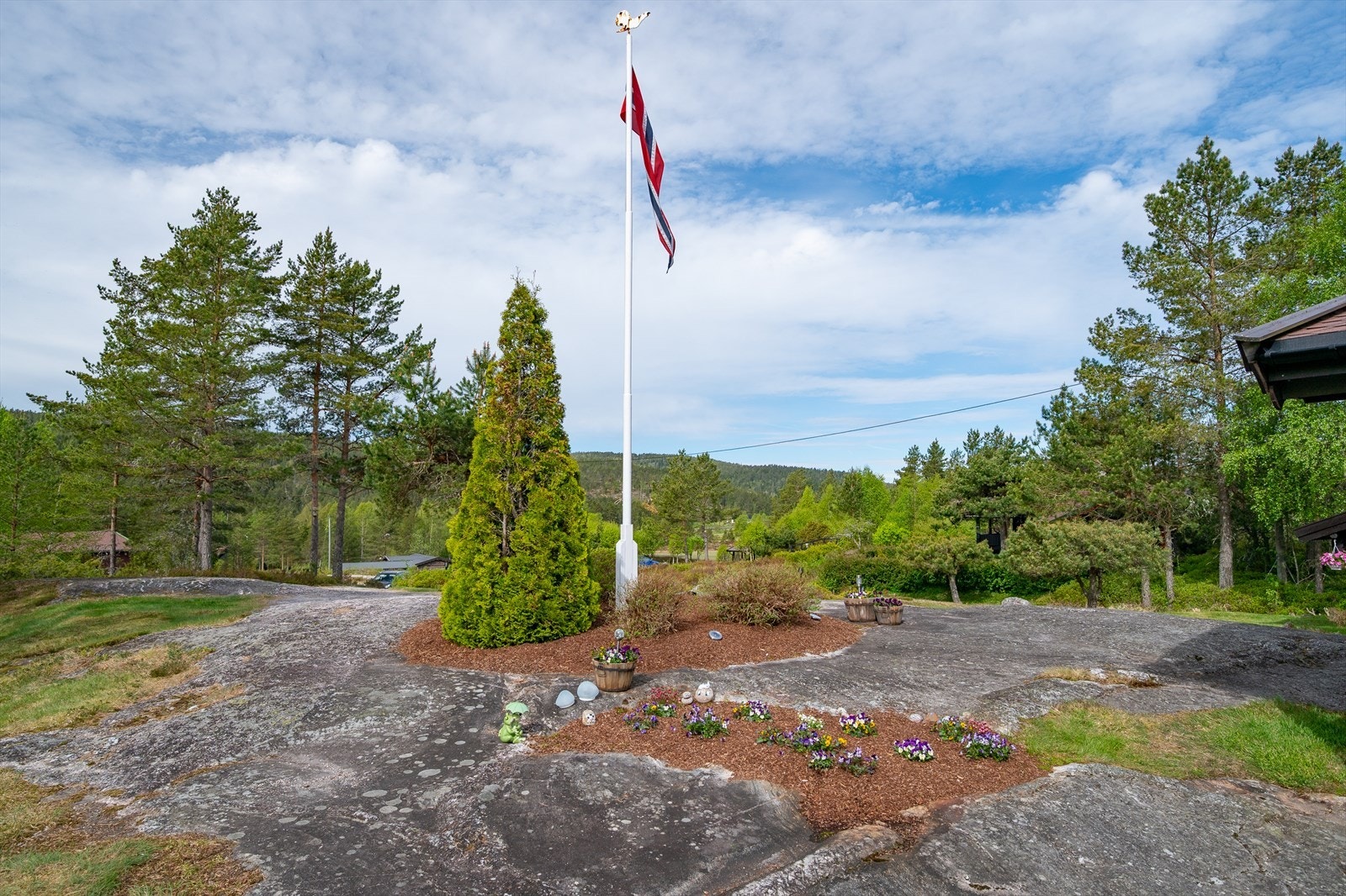 Velstelt eiendom med blomsterbed og flaggstang Galleribilde