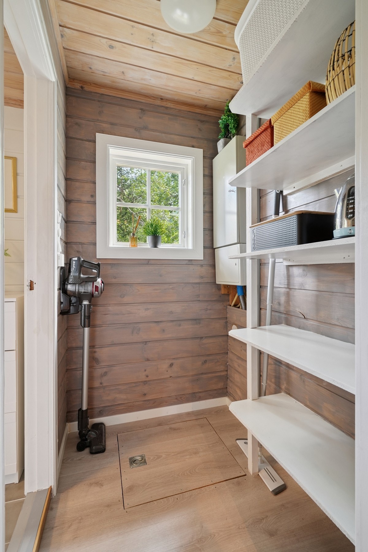 Gang ved kjøkkenet og inn til badet har plassbygd hyller og luke til rom i kjeller. Rommet i kjelleren blir brukt som et naturlig kjølerom. Galleribilde