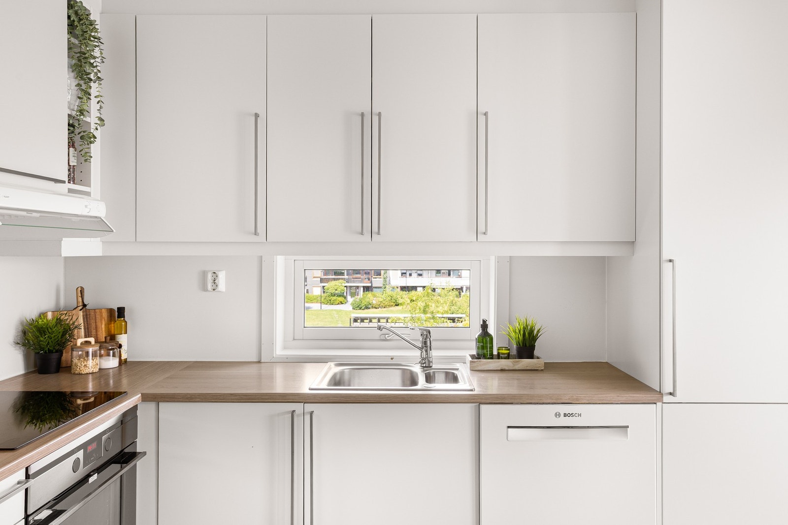 Lys, glatt innredning med laminat benkeplate og nedfelt stålvask med ett-greps blandebatteri. Galleribilde