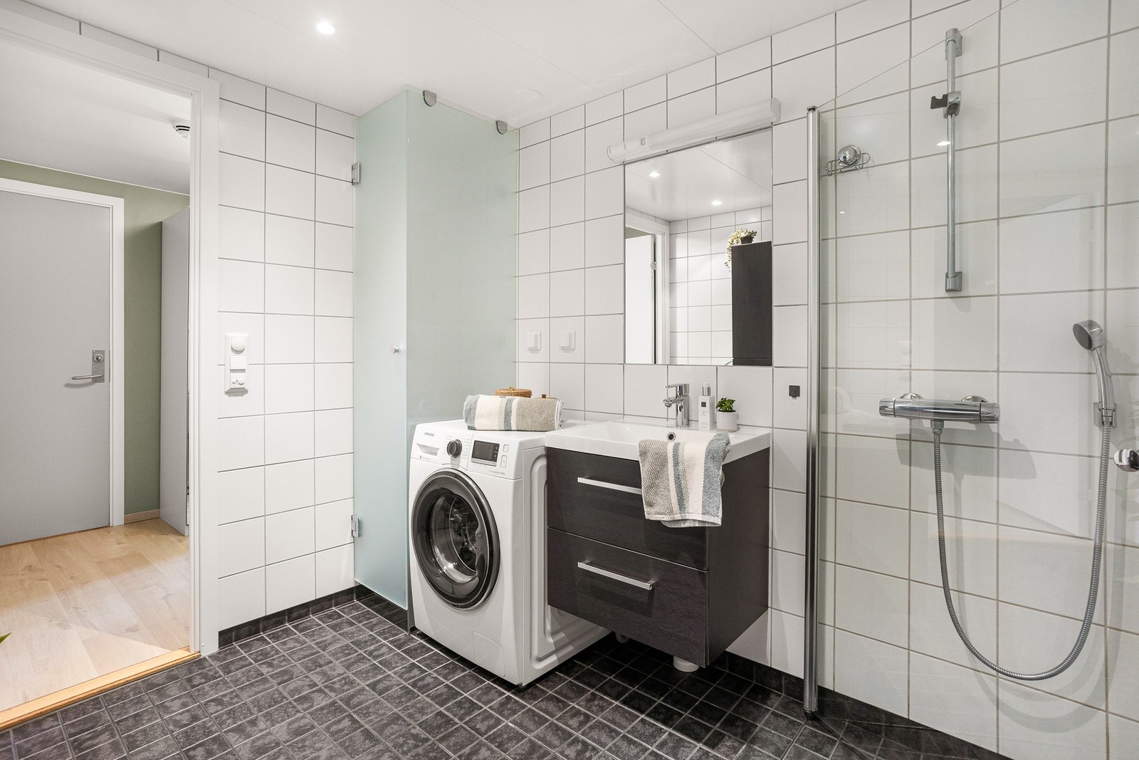 Innredningen består av servant på underskuffer, høyskap, speil, vegghengt toalett og dusjhjørne. Galleribilde