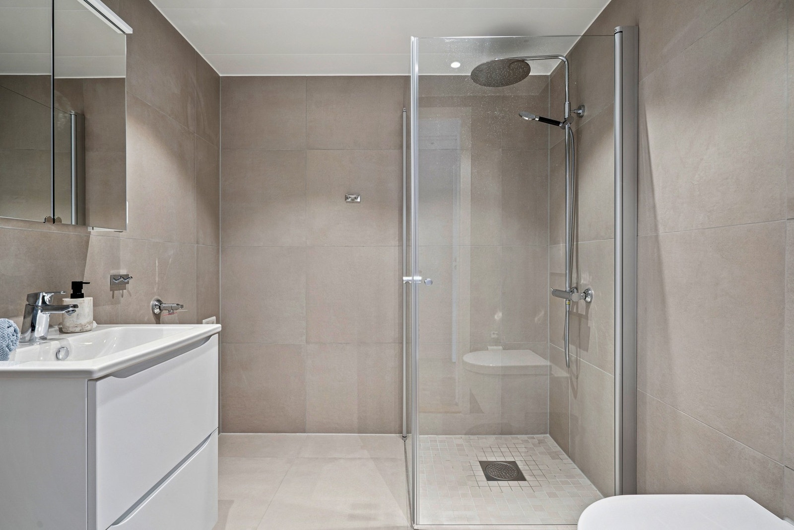 Badet er komplett flislagt i et lunt og behagelig fargevalg. Galleribilde