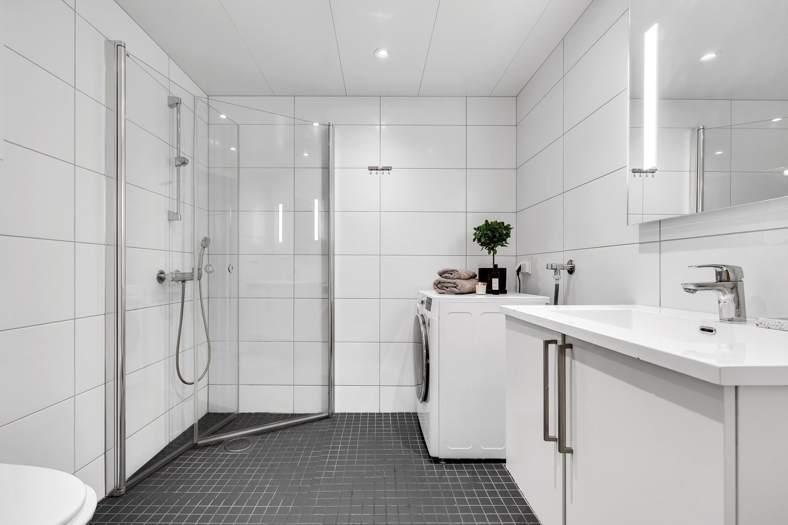 Det delikate baderommet på 4,5 m² er flislagt fra topp til tå med elektrisk gulvvarme. Baderomsinnredningen har gode oppbevaringsmuligheter for håndduker og baderomsartikler. Moderne downlights i tak gir en optimal lyssetting. Galleribilde