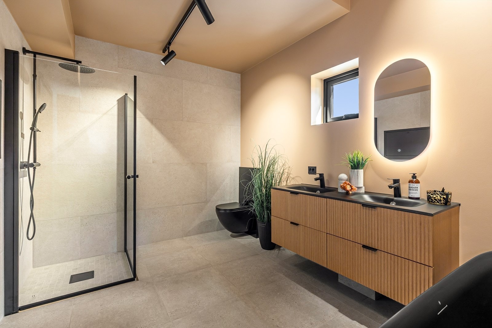 Stort og stilrent baderom med flislagt gulv og kontrastvegger. Galleribilde