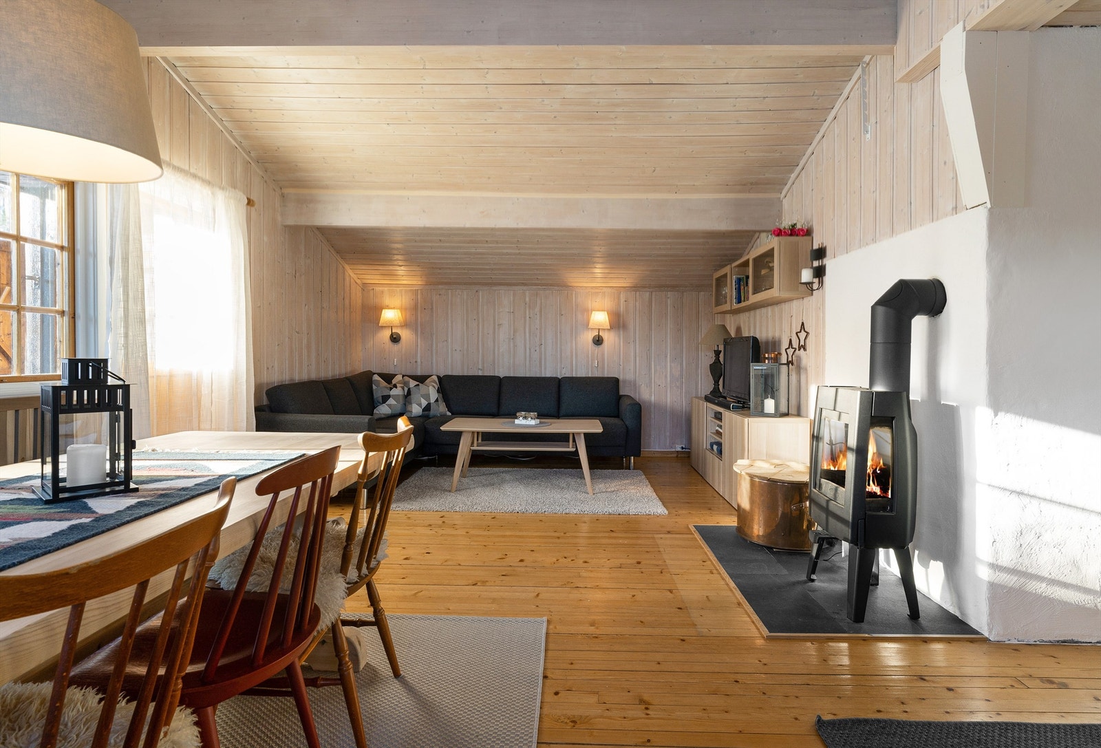 Stuen har hvitbeiset paneltak, hvitbeisede panelvegger og tregulv. Det er en nyere peisovn som varmer godt på vinterstid. Galleribilde